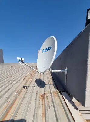 DStv satellite dish on metal roof against clear blue sky